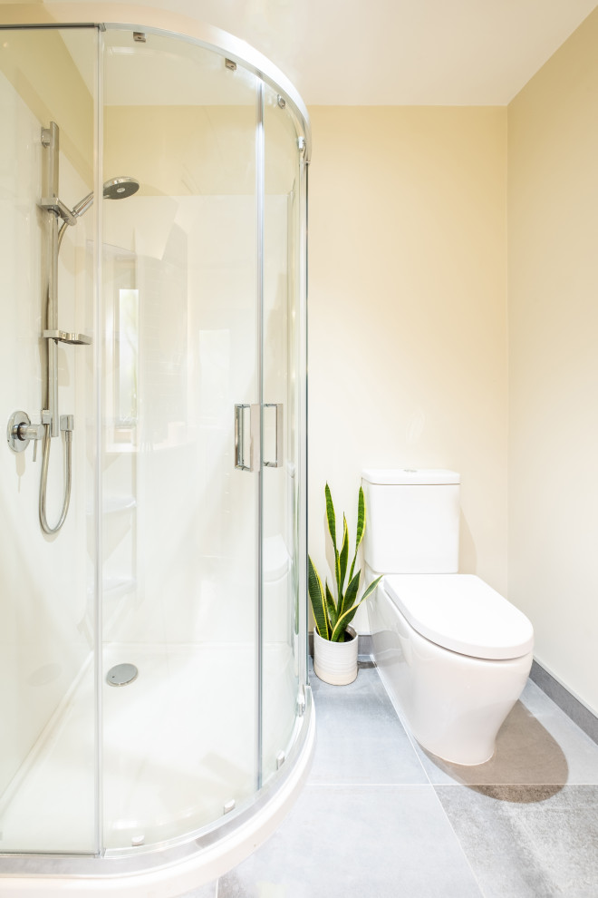 Bild på ett mellanstort funkis vit vitt en-suite badrum, med skåp i mellenmörkt trä, en hörndusch, blå kakel, bänkskiva i akrylsten, dusch med skjutdörr, en toalettstol med hel cisternkåpa, keramikplattor, vita väggar, klinkergolv i keramik, ett fristående handfat och grått golv