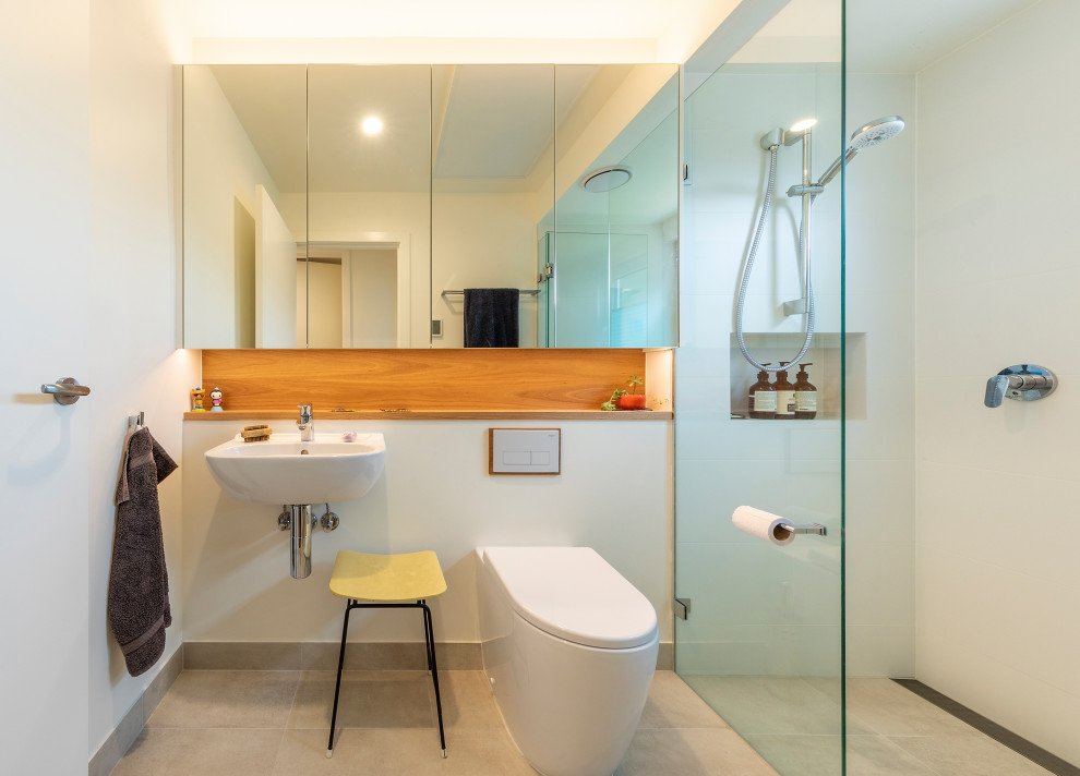 Inspiration for a small contemporary master bathroom in Canberra - Queanbeyan with glass-front cabinets, a wall-mount toilet, white tile, ceramic tile, white walls, ceramic floors, a wall-mount sink, beige floor, an open shower, a single vanity and a floating vanity.