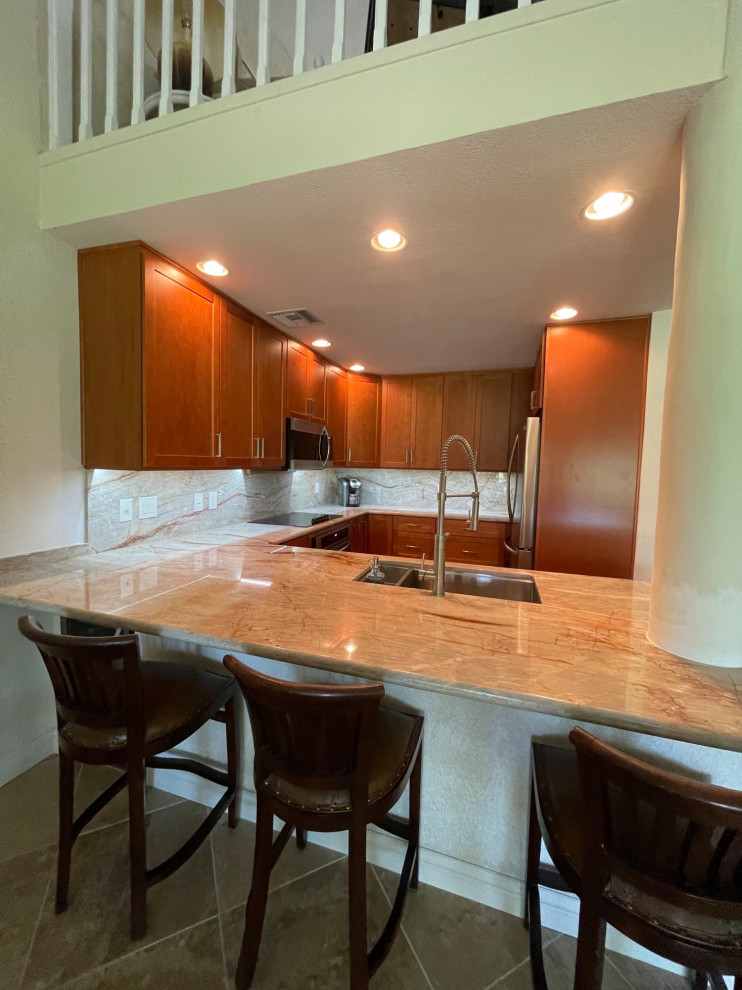 Example of a small transitional u-shaped open concept kitchen design with an undermount sink, shaker cabinets, brown cabinets, quartzite countertops, beige backsplash, stainless steel appliances, a peninsula and beige countertops