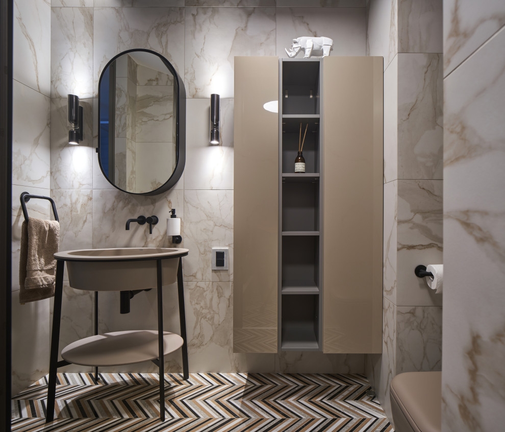 Inspiration for a mid-sized contemporary powder room in Yekaterinburg with flat-panel cabinets, beige cabinets, a wall-mount toilet, multi-coloured tile, ceramic tile, beige walls, ceramic floors, a pedestal sink, solid surface benchtops, multi-coloured floor, beige benchtops, a freestanding vanity, wood and panelled walls.