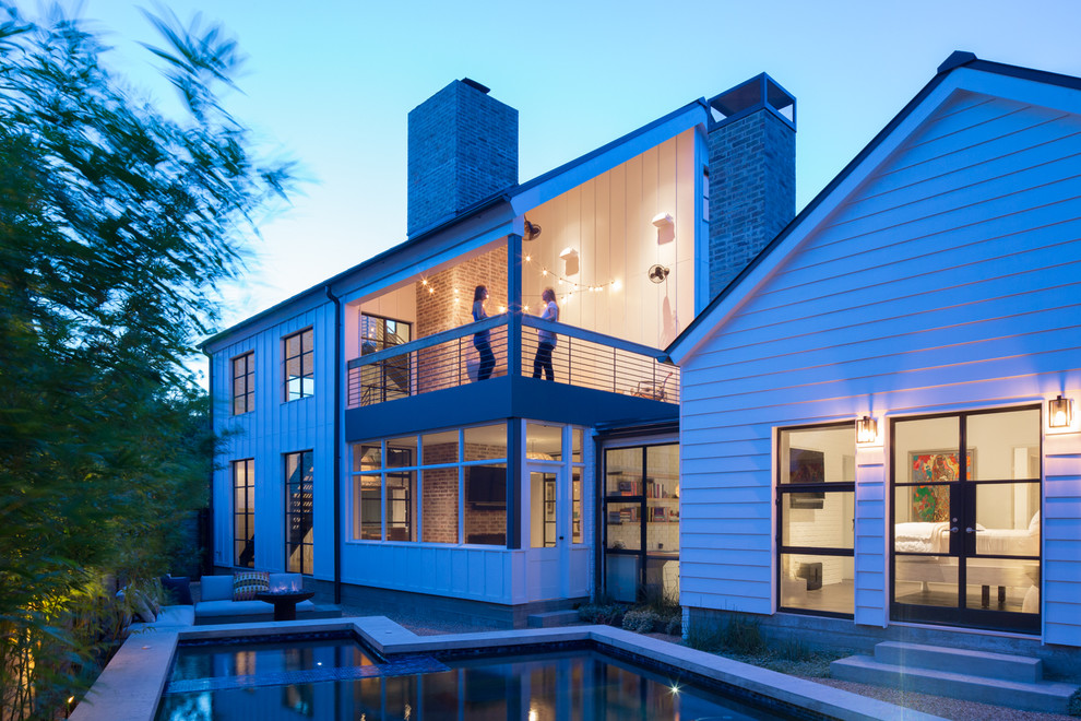 Photo of a mid-sized modern three-storey white house exterior in Austin with a gable roof and a metal roof.