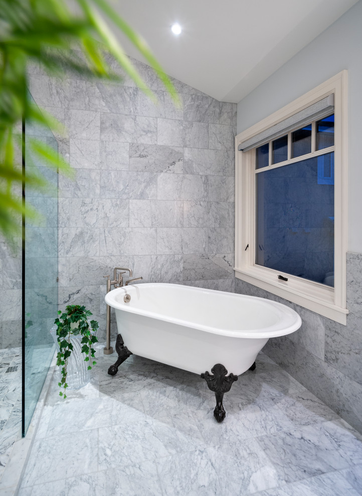 Amerikansk inredning av ett stort vit vitt en-suite badrum, med möbel-liknande, svarta skåp, ett badkar med tassar, en kantlös dusch, en bidé, vit kakel, marmorkakel, vita väggar, marmorgolv, ett undermonterad handfat, marmorbänkskiva, vitt golv och med dusch som är öppen