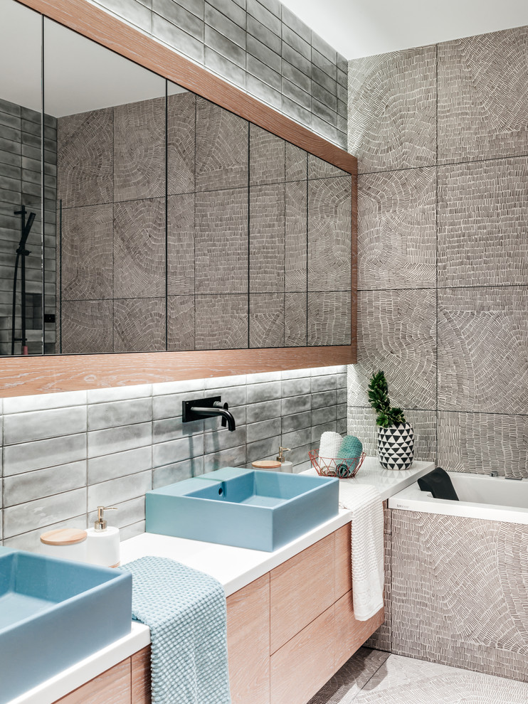 This is an example of a contemporary master bathroom in Moscow with flat-panel cabinets, light wood cabinets, gray tile, a vessel sink, grey floor, white benchtops and an alcove tub.
