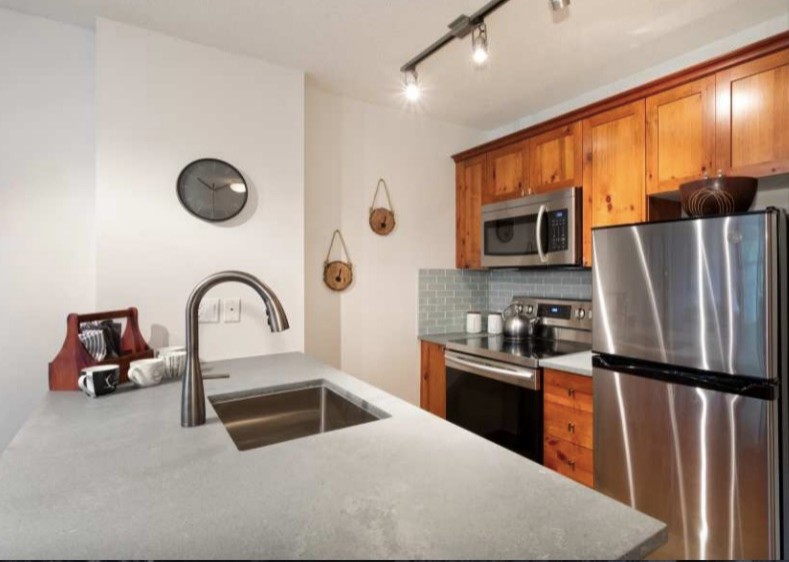Example of a small transitional galley eat-in kitchen design with an undermount sink, concrete countertops, gray backsplash, glass tile backsplash, stainless steel appliances and gray countertops