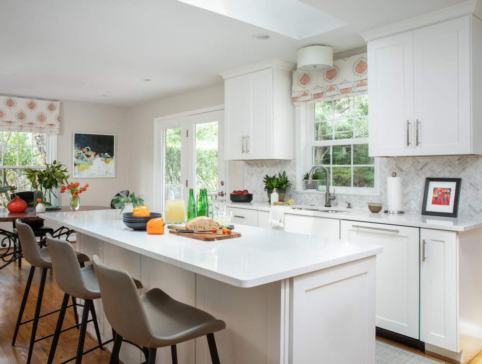 This is an example of a transitional kitchen in DC Metro with a double-bowl sink, shaker cabinets, white cabinets, quartz benchtops, white splashback, marble splashback, stainless steel appliances, medium hardwood floors, with island and white benchtop.