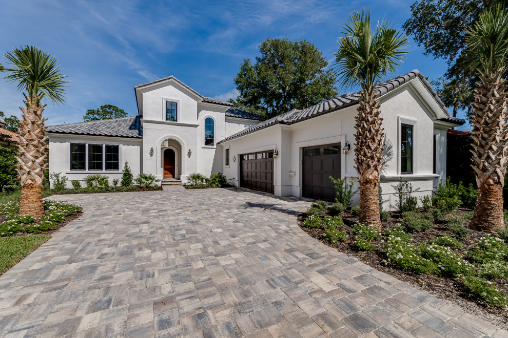 Photo of a large mediterranean two-storey stucco white house exterior in Jacksonville with a gable roof, a tile roof and a grey roof.