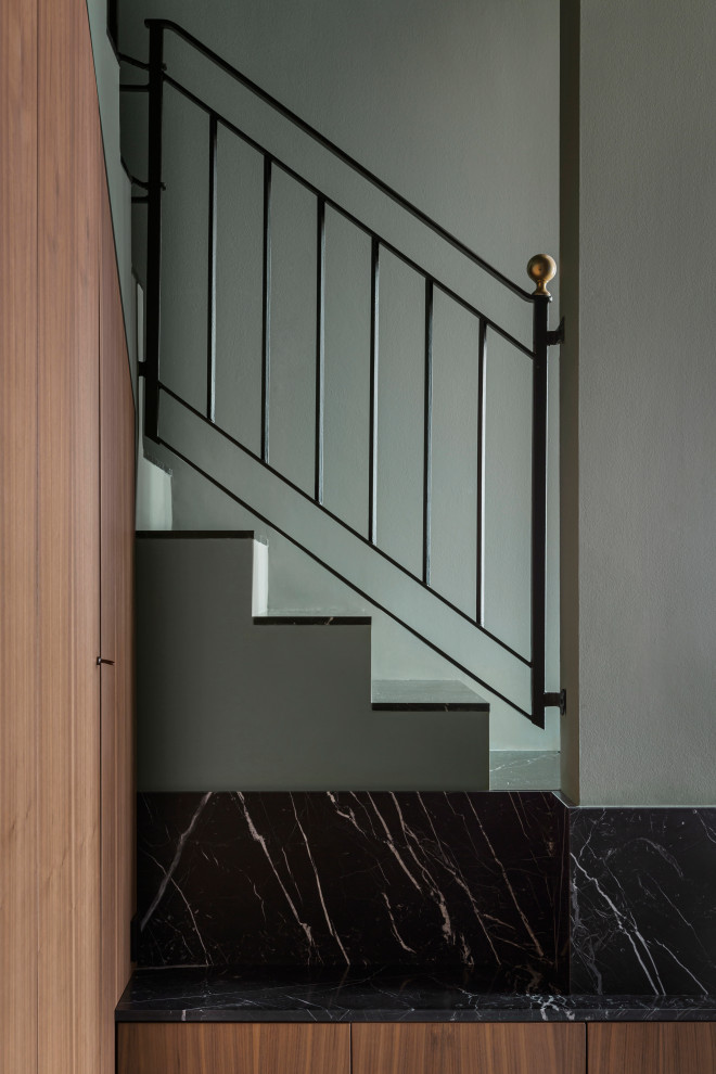 Diseño de escalera en U contemporánea de tamaño medio con escalones de mármol, contrahuellas de hormigón, barandilla de metal y boiserie