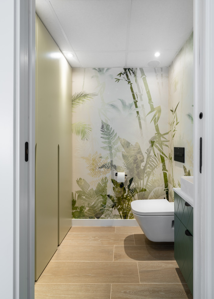 This is an example of a small contemporary powder room in Other with raised-panel cabinets, green cabinets, laminate benchtops, a floating vanity and wallpaper.