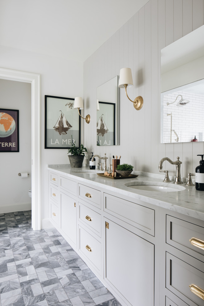 This is an example of a transitional bathroom in Grand Rapids with recessed-panel cabinets, grey cabinets, an alcove shower, white tile, ceramic tile, white walls, marble floors, an undermount sink, marble benchtops, grey floor, an open shower, white benchtops, a double vanity, a built-in vanity and panelled walls.