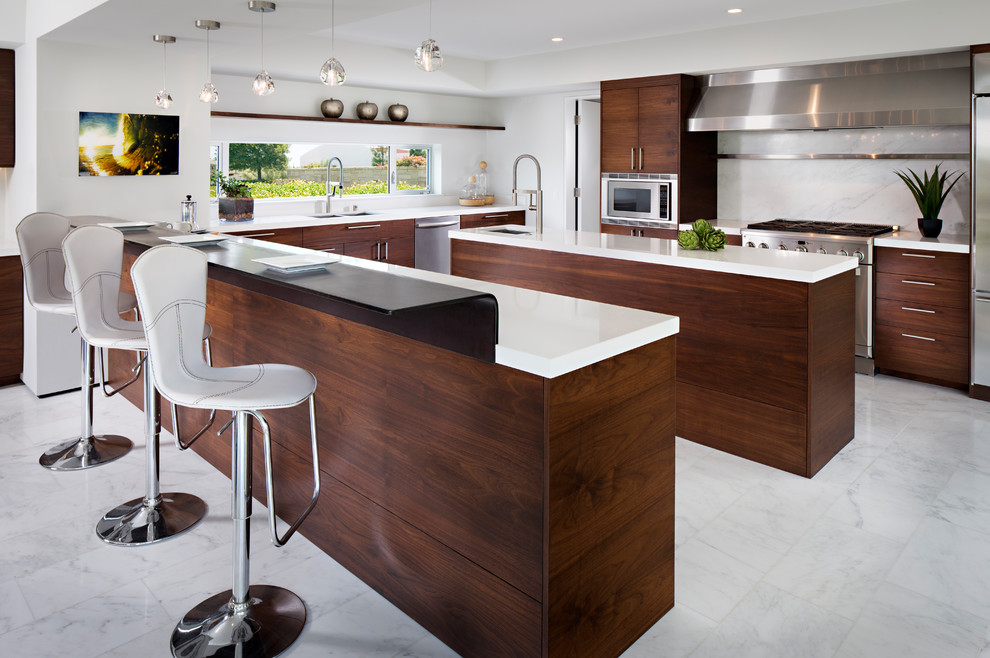 This is an example of a contemporary kitchen in San Diego with an undermount sink, flat-panel cabinets, dark wood cabinets, white splashback, stone slab splashback, stainless steel appliances, multiple islands and white floor.