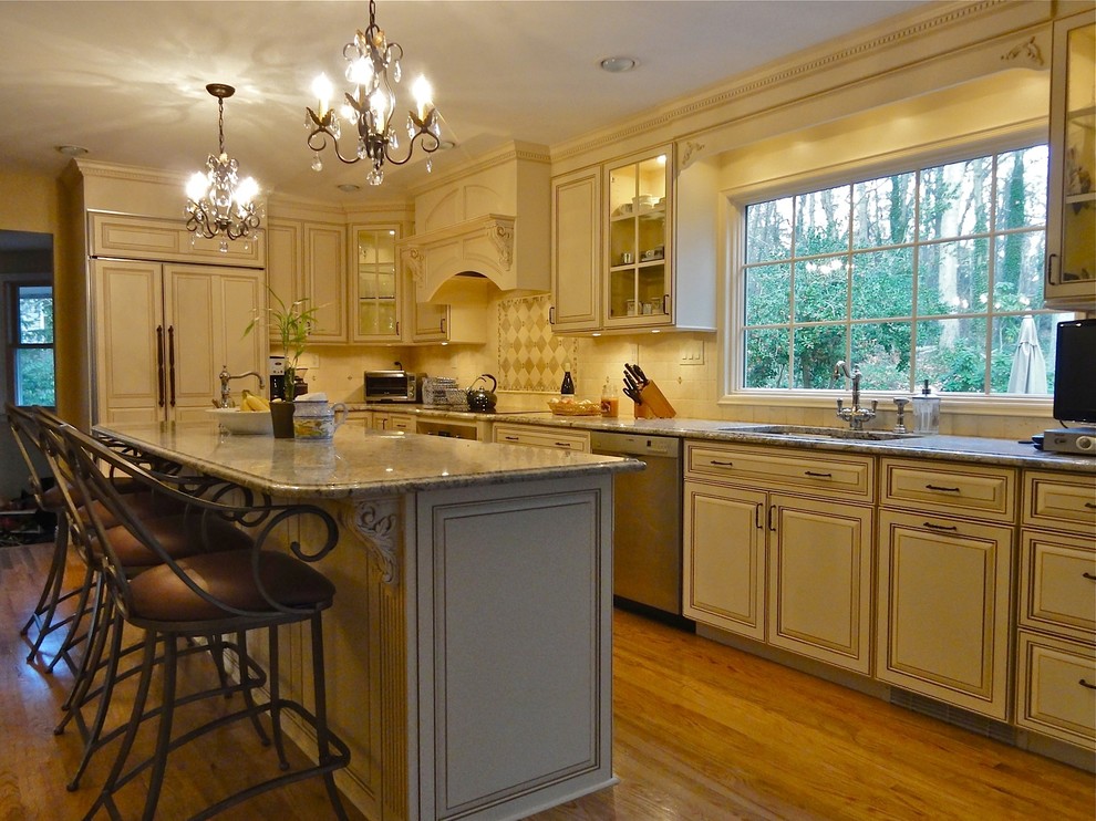 Traditional l-shaped eat-in kitchen in New York with an undermount sink, raised-panel cabinets, white cabinets and panelled appliances.