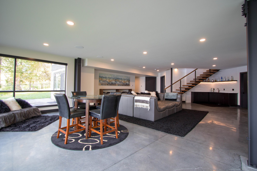 This is an example of a modern walk-out basement in Other with a home bar, grey walls and concrete floors.