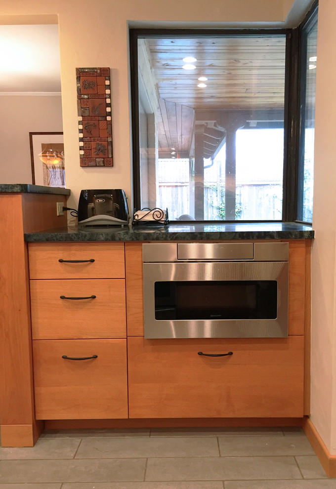 Photo of a mid-sized midcentury galley eat-in kitchen in Other with an integrated sink, flat-panel cabinets, medium wood cabinets, soapstone benchtops, white splashback, ceramic splashback, stainless steel appliances, ceramic floors, no island and grey floor.