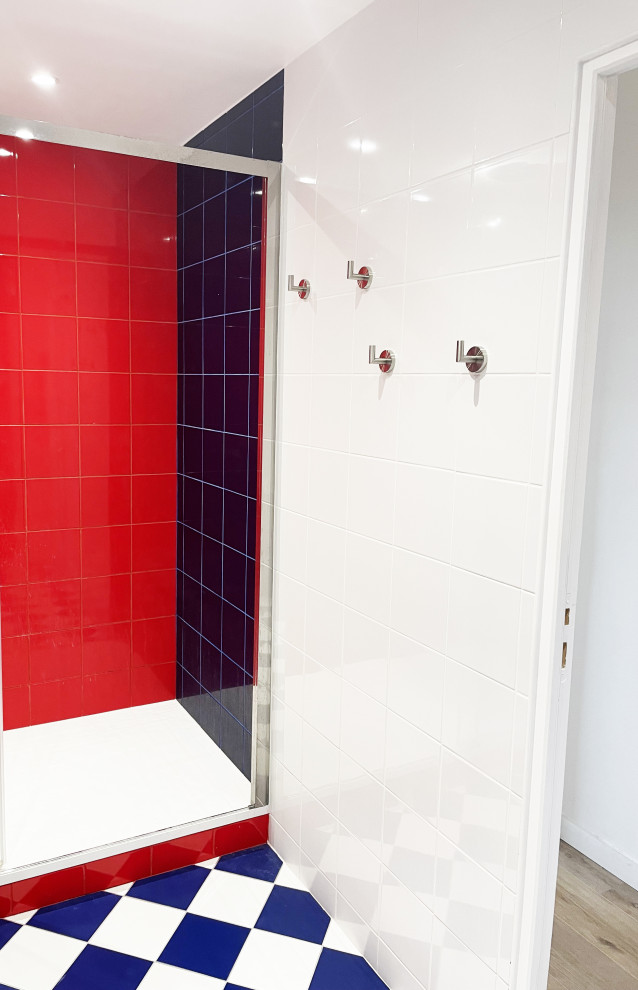 This is an example of a small transitional master bathroom in Paris with flat-panel cabinets, blue cabinets, a curbless shower, a two-piece toilet, red tile, ceramic tile, blue walls, ceramic floors, an integrated sink, solid surface benchtops, blue floor, a sliding shower screen, white benchtops, a double vanity and a built-in vanity.