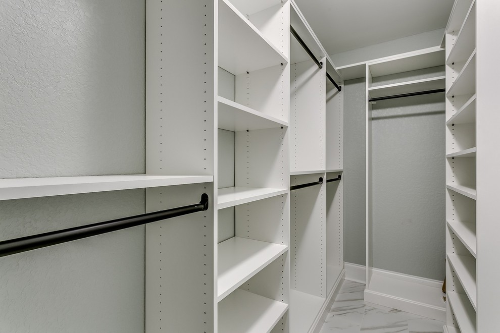 Mid-sized traditional gender-neutral walk-in wardrobe in Other with open cabinets, white cabinets and porcelain floors.
