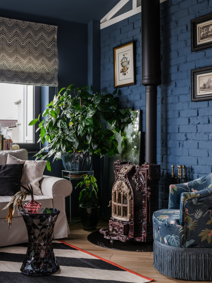 This is an example of a large bohemian mezzanine living room feature wall in Moscow with a reading nook, blue walls, medium hardwood flooring, a wood burning stove, a metal fireplace surround, no tv, brown floors, a vaulted ceiling and brick walls.