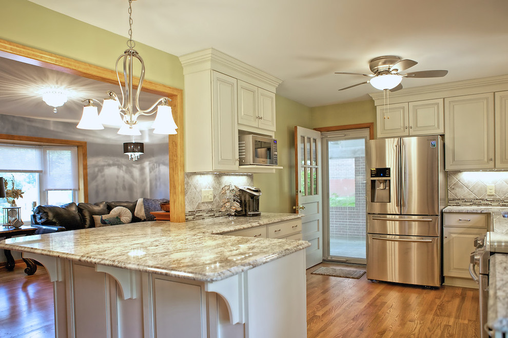 Large transitional u-shaped medium tone wood floor eat-in kitchen photo with raised-panel cabinets, white cabinets, granite countertops, gray backsplash, stainless steel appliances, yellow walls, a peninsula, a single-bowl sink and ceramic backsplash