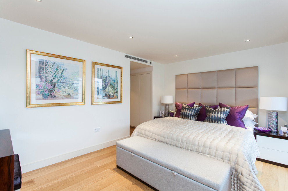 Photo of a contemporary bedroom in London with white walls and medium hardwood floors.