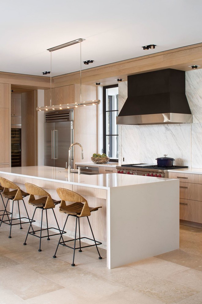 Photo of a mid-sized contemporary galley eat-in kitchen in San Francisco with a farmhouse sink, flat-panel cabinets, distressed cabinets, solid surface benchtops, white splashback, stone slab splashback, stainless steel appliances, travertine floors and with island.
