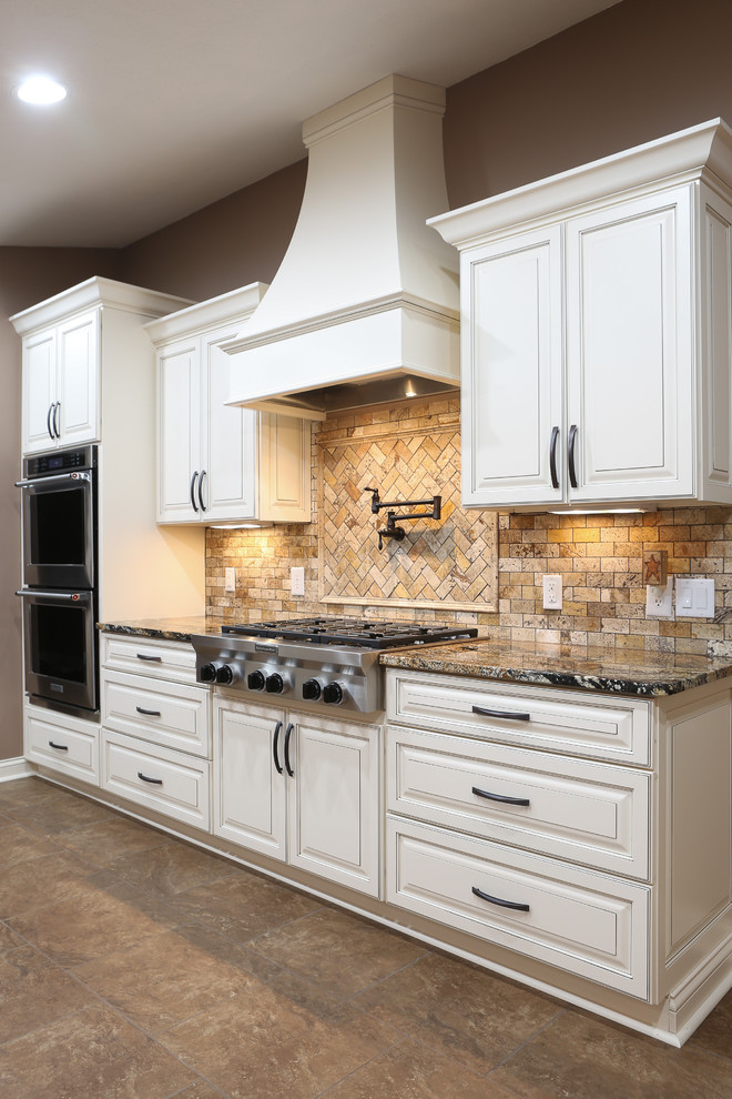 Inspiration for a large transitional u-shaped porcelain tile and brown floor open concept kitchen remodel with a farmhouse sink, raised-panel cabinets, white cabinets, granite countertops, beige backsplash, travertine backsplash, stainless steel appliances and an island