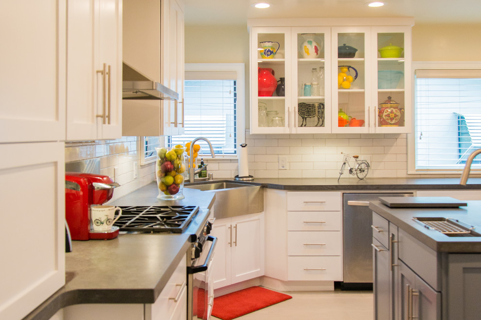 Kitchen - transitional porcelain tile kitchen idea in Sacramento with a farmhouse sink, shaker cabinets, white cabinets, white backsplash, subway tile backsplash, stainless steel appliances and an island