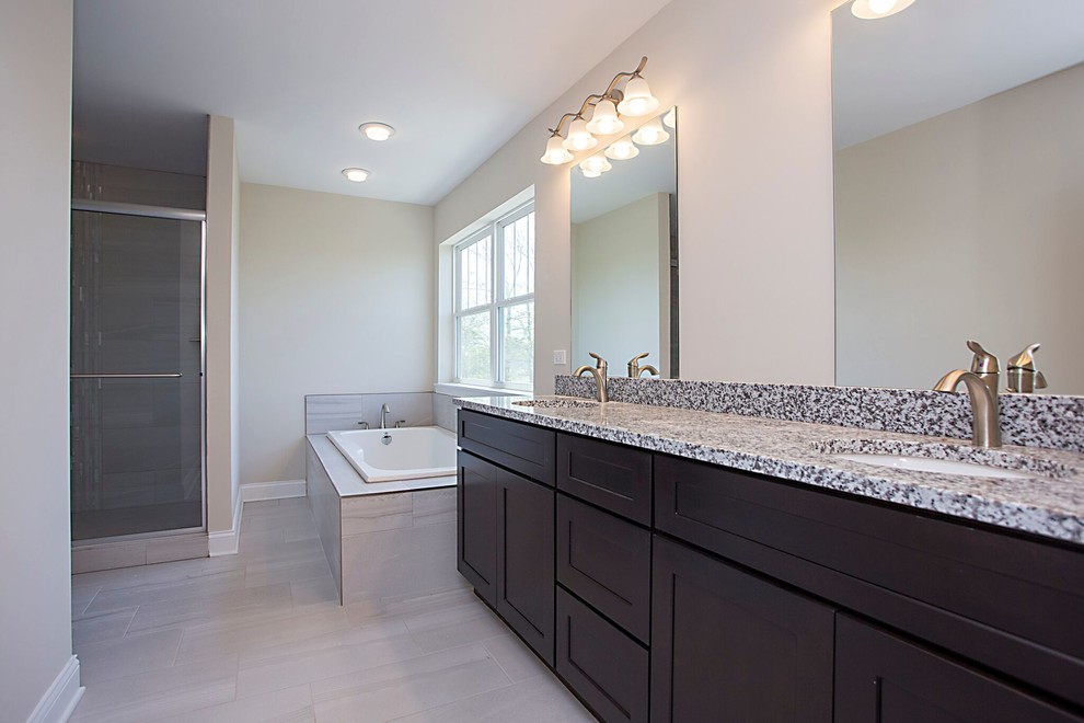 Large transitional master porcelain tile and beige floor drop-in bathtub photo in Chicago with recessed-panel cabinets, dark wood cabinets, beige walls, an undermount sink, granite countertops and a hinged shower door