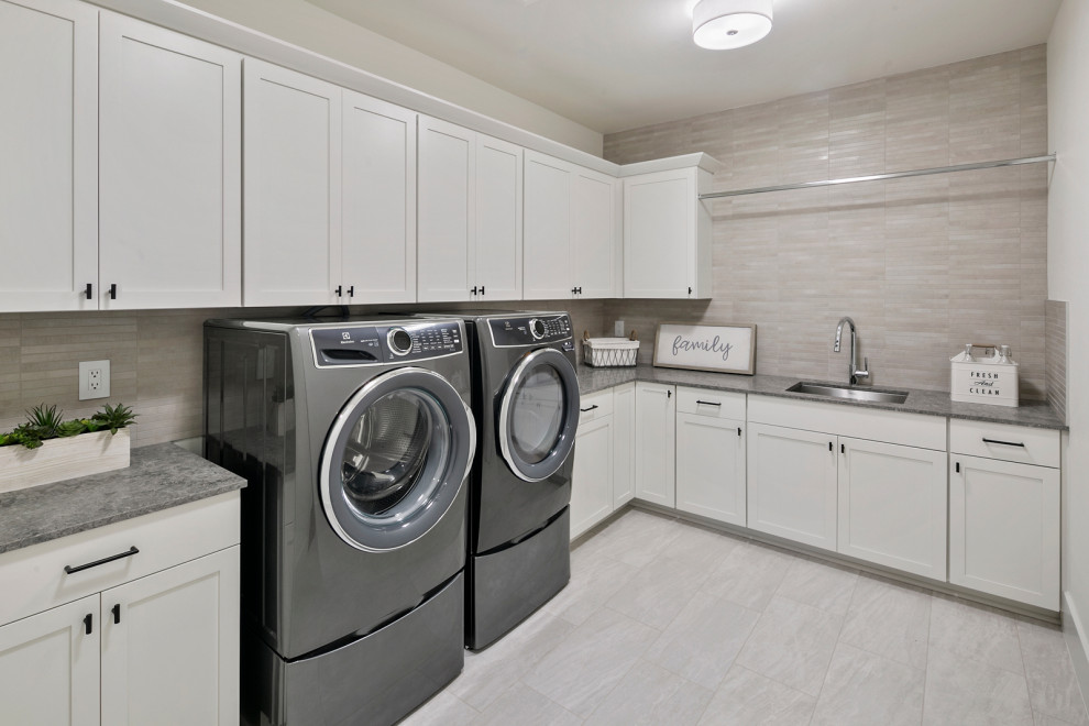 Inspiration for a large l-shaped dedicated laundry room in Seattle with a drop-in sink, recessed-panel cabinets, white cabinets, quartz benchtops, grey splashback, cement tile splashback, white walls, ceramic floors, a side-by-side washer and dryer, grey floor and grey benchtop.