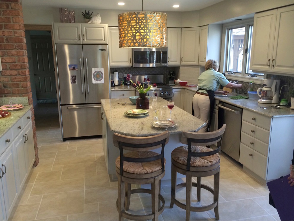 Example of a mid-sized transitional u-shaped travertine floor eat-in kitchen design with a double-bowl sink, beaded inset cabinets, beige cabinets, granite countertops, stainless steel appliances, an island, gray backsplash and porcelain backsplash