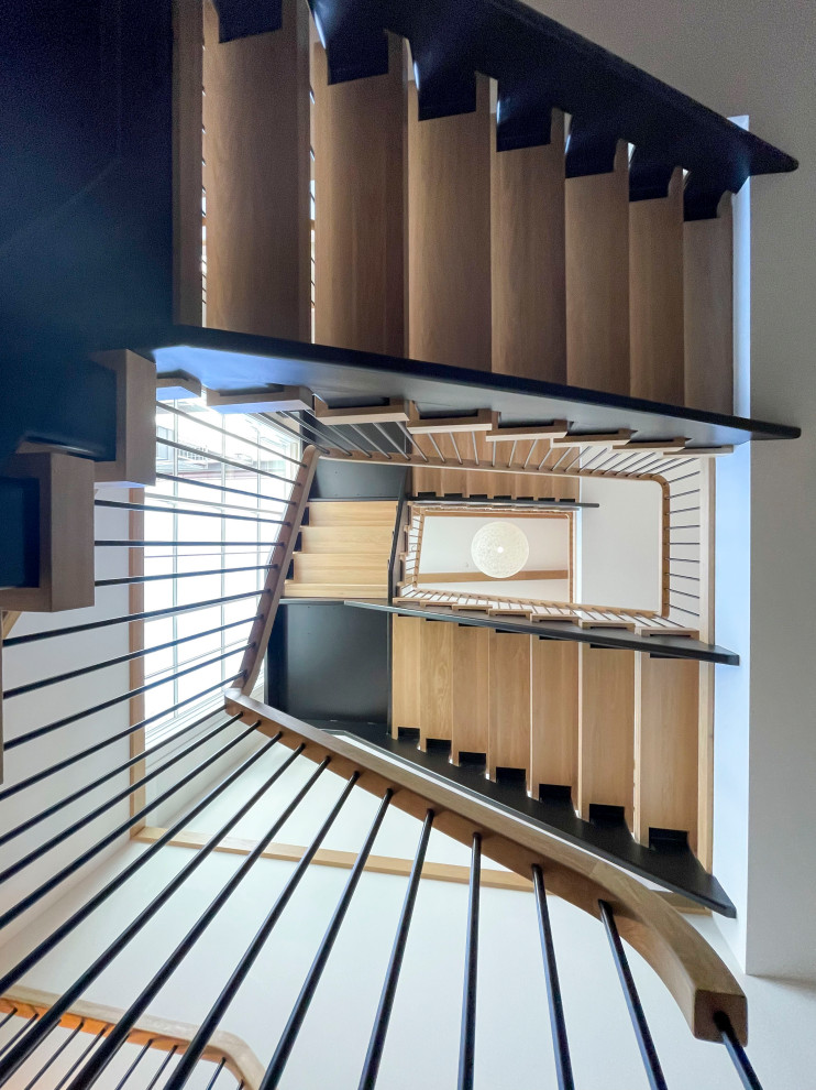 This is an example of an expansive modern wood floating staircase in DC Metro with mixed railing and planked wall panelling.