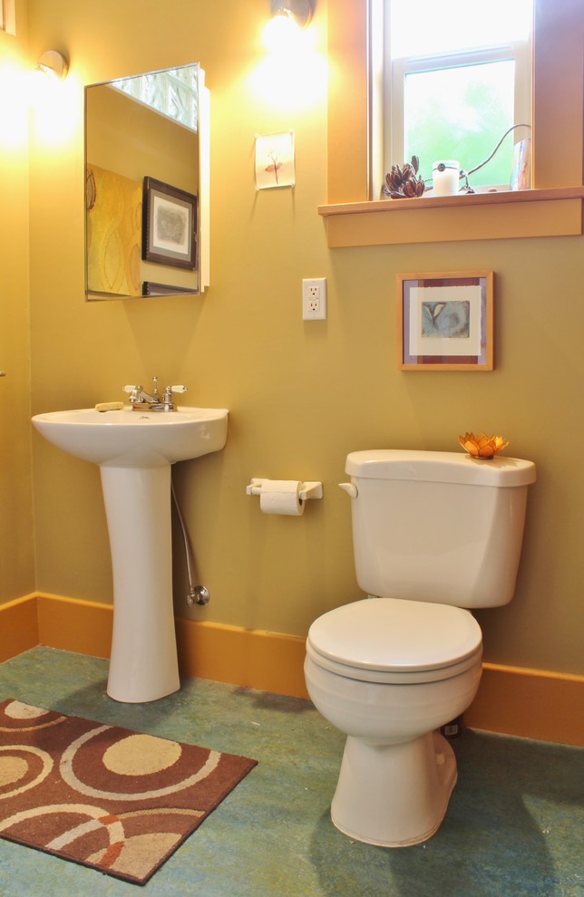 This is an example of a small arts and crafts bathroom in Seattle with a pedestal sink, yellow walls and linoleum floors.