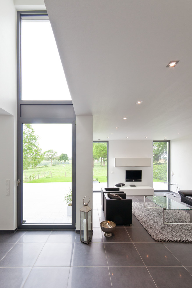 Large contemporary open concept family room in Cologne with white walls and a wall-mounted tv.