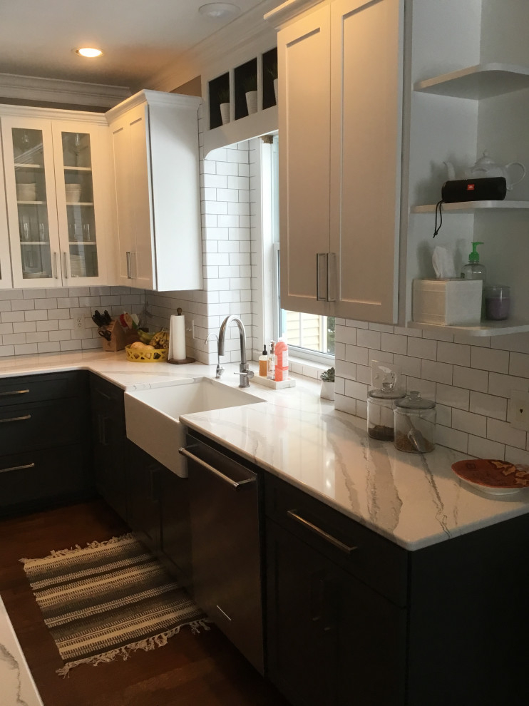 Mid-sized transitional l-shaped dark wood floor and red floor eat-in kitchen photo with a farmhouse sink, recessed-panel cabinets, gray cabinets, stainless steel appliances, an island, white countertops, quartz countertops, white backsplash and subway tile backsplash