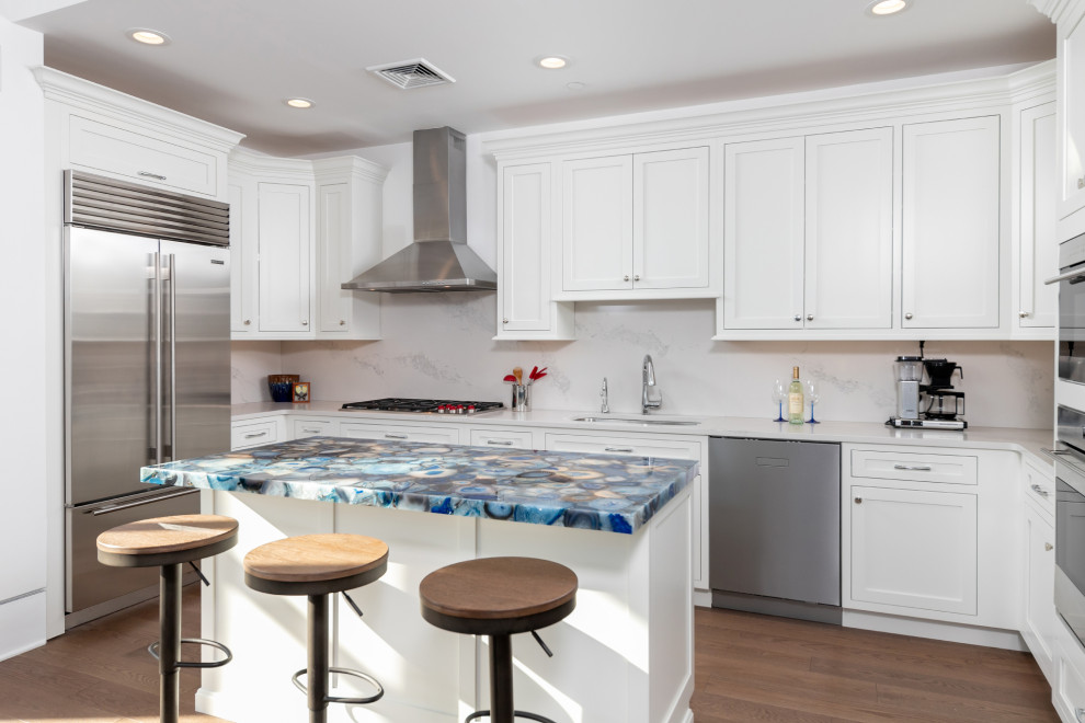 Design ideas for a mid-sized transitional galley eat-in kitchen in Philadelphia with a double-bowl sink, shaker cabinets, white cabinets, white splashback, marble splashback, stainless steel appliances, medium hardwood floors, with island, brown floor and blue benchtop.