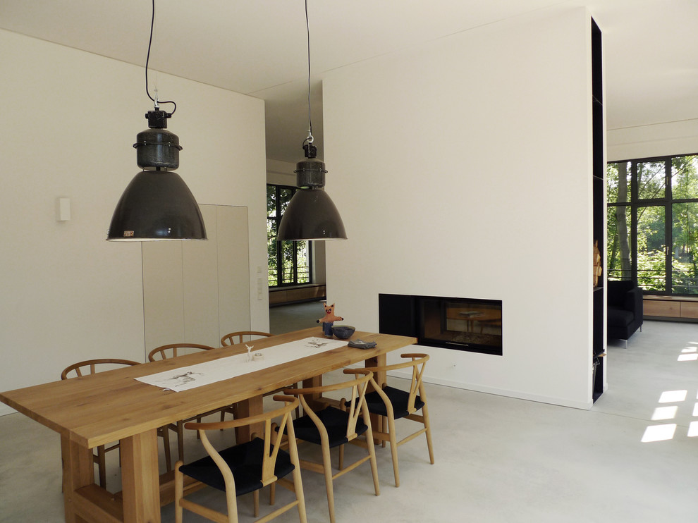 Photo of a large scandinavian dining room in Berlin with white walls and concrete floors.