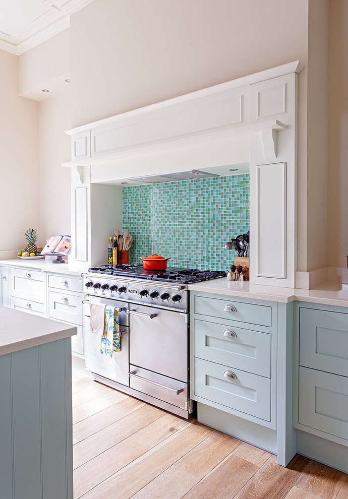 Inspiration for a traditional eat-in kitchen in Edinburgh with shaker cabinets, blue cabinets, blue splashback, mosaic tile splashback, light hardwood floors and with island.