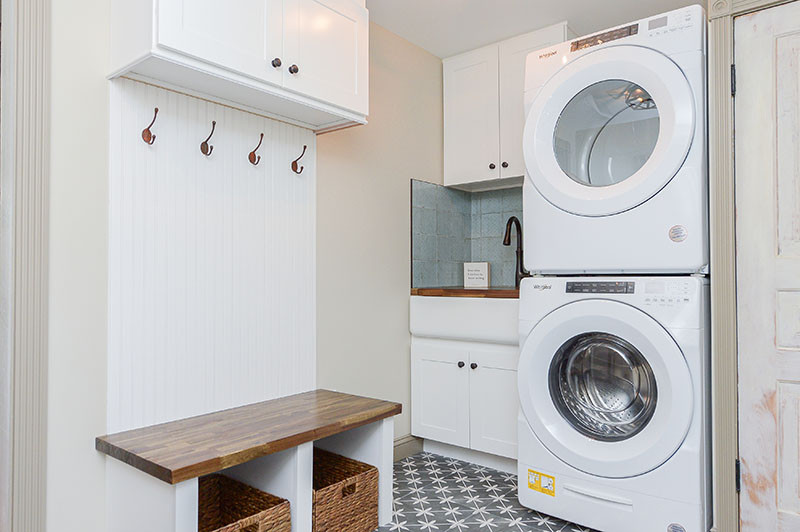 Example of a mid-sized cottage single-wall utility room design in Philadelphia with an undermount sink, beige walls and a stacked washer/dryer