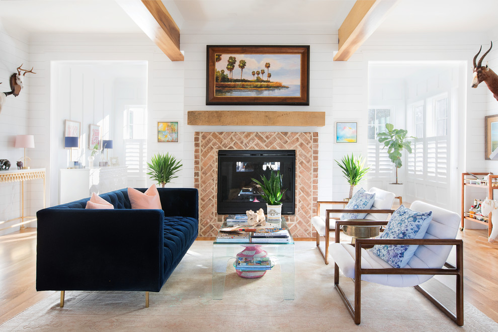 Design ideas for a beach style living room in Charleston with white walls, medium hardwood floors, a standard fireplace and brown floor.