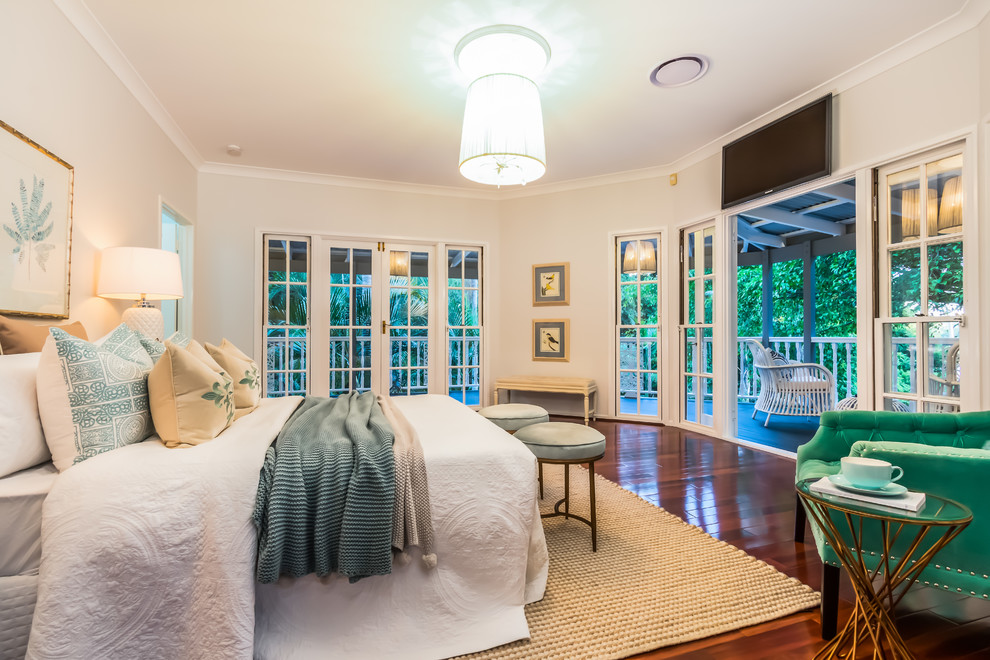 This is an example of a mid-sized beach style master bedroom in Brisbane with beige walls, dark hardwood floors and brown floor.
