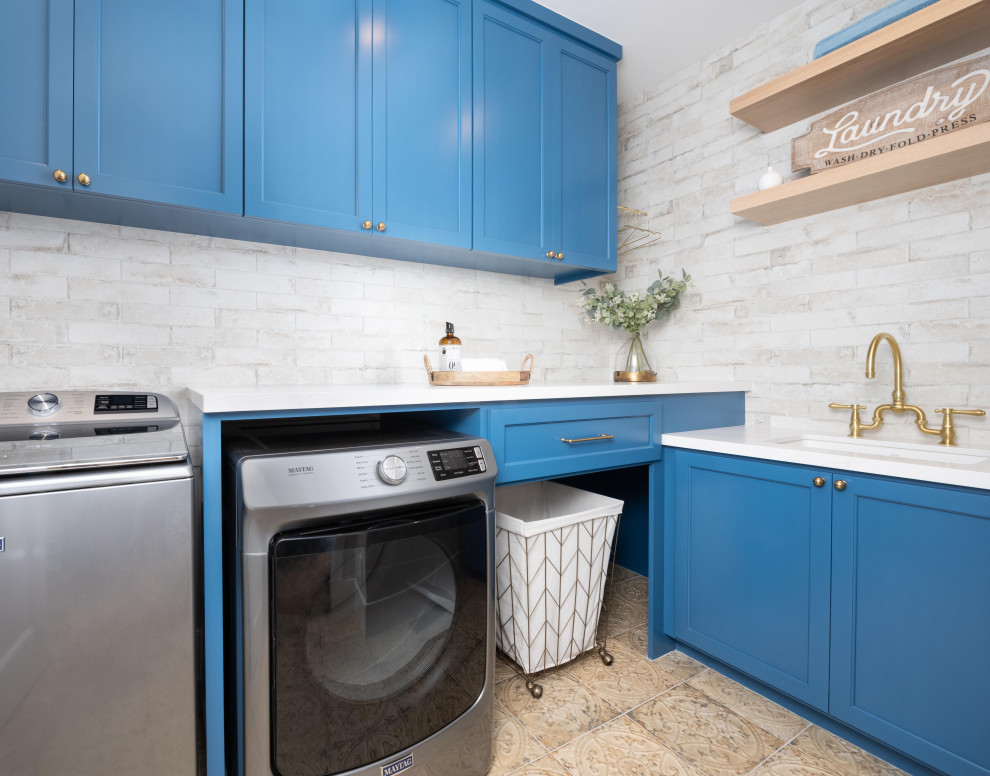 サンフランシスコにある高級な中くらいなトランジショナルスタイルのおしゃれな洗濯室 (L型、アンダーカウンターシンク、シェーカースタイル扉のキャビネット、青いキャビネット、クオーツストーンカウンター、ベージュキッチンパネル、セラミックタイルのキッチンパネル、ベージュの壁、左右配置の洗濯機・乾燥機、ベージュの床、白いキッチンカウンター) の写真