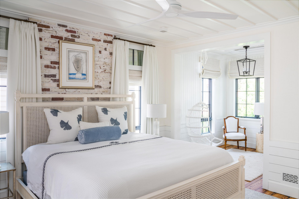 Beach style bedroom in Charleston with multi-coloured walls, medium hardwood floors, brown floor and brick walls.