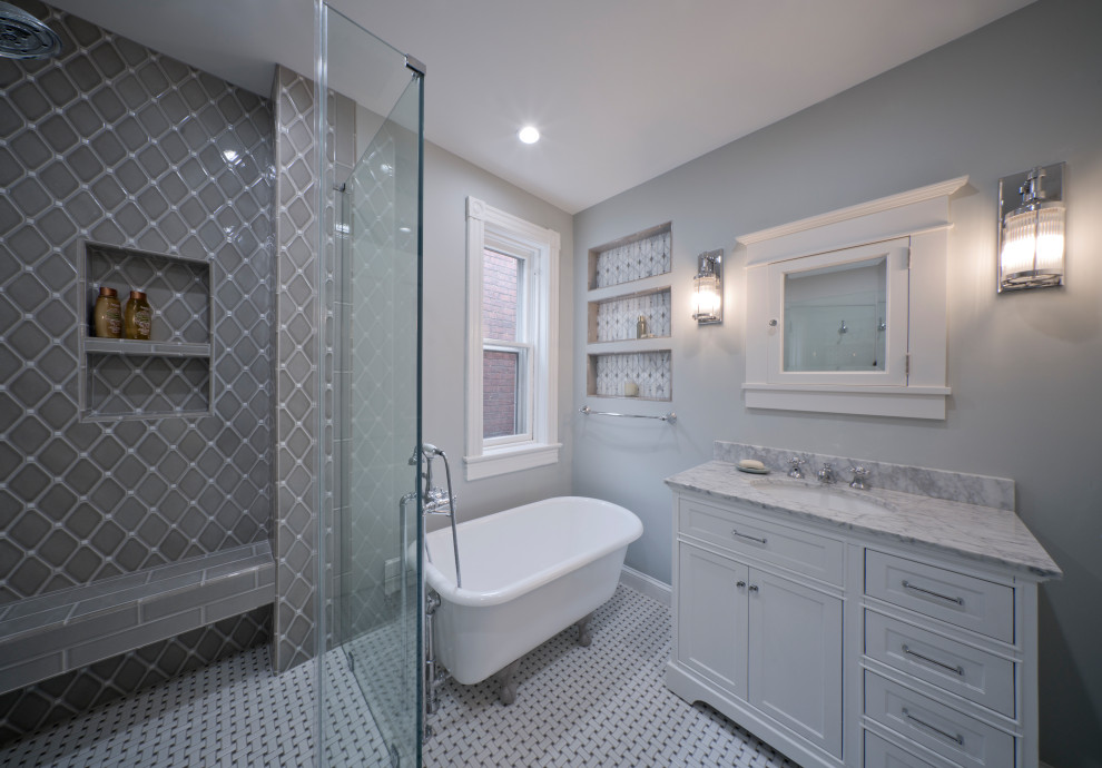 Exemple d'une salle de bain principale victorienne de taille moyenne avec un placard à porte plane, des portes de placard blanches, une baignoire sur pieds, une douche d'angle, WC séparés, un carrelage gris, des carreaux de céramique, un mur gris, un sol en carrelage de céramique, un lavabo encastré, un plan de toilette en marbre, un sol blanc, une cabine de douche à porte battante, un plan de toilette blanc, une niche, meuble simple vasque et meuble-lavabo sur pied.
