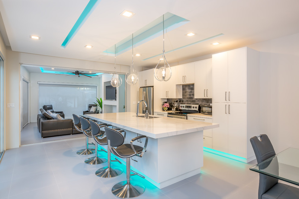 Design ideas for a contemporary galley kitchen in Miami with an undermount sink, flat-panel cabinets, white cabinets, grey splashback, stainless steel appliances, with island, grey floor and white benchtop.