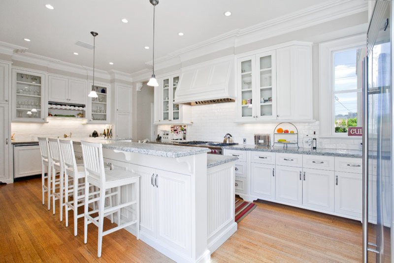 Inspiration for a large contemporary l-shaped open plan kitchen in San Francisco with a double-bowl sink, louvered cabinets, white cabinets, marble benchtops, white splashback, subway tile splashback, stainless steel appliances, medium hardwood floors and with island.