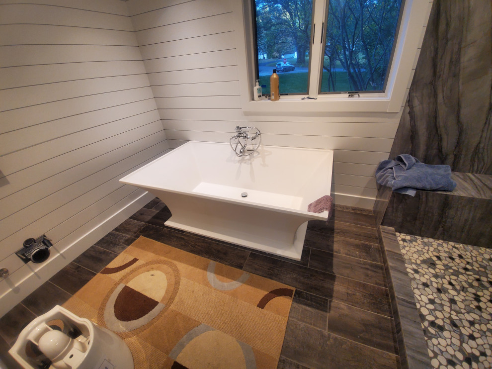This is an example of a large country master bathroom in Chicago with shaker cabinets, white cabinets, a freestanding tub, an alcove shower, a bidet, white tile, white walls, wood-look tile, a drop-in sink, engineered quartz benchtops, brown floor, a hinged shower door, white benchtops, a double vanity, a built-in vanity, timber and planked wall panelling.