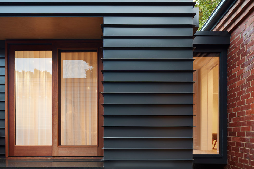 Inspiration for a mid-sized contemporary one-storey black house exterior in Canberra - Queanbeyan with metal siding, a flat roof and a metal roof.