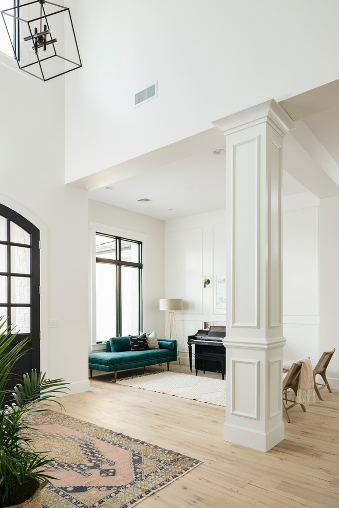Example of a large transitional light wood floor and beige floor foyer design in Phoenix with white walls and a black front door