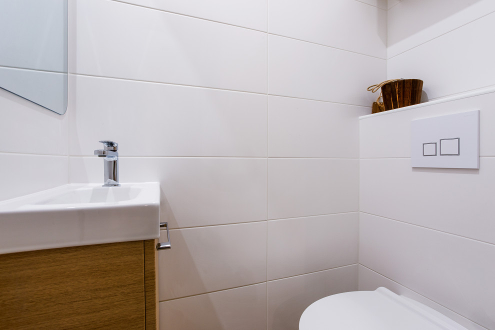 Foto de aseo contemporáneo pequeño con sanitario de pared, baldosas y/o azulejos blancos, paredes blancas, imitación a madera, lavabo integrado y suelo beige