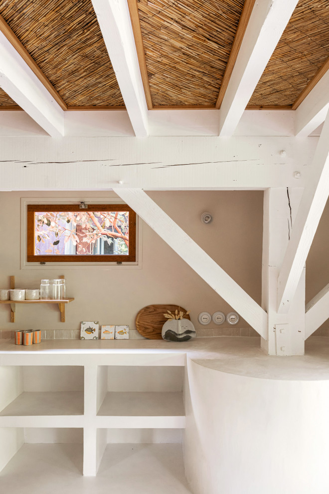 Immagine di un soggiorno mediterraneo aperto con pareti beige, pavimento in cemento, pavimento bianco, soffitto in legno e carta da parati