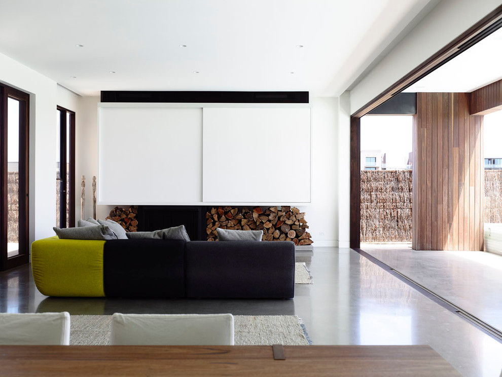 Large contemporary formal open concept living room in Melbourne with white walls, concrete floors, a wood stove, a wood fireplace surround and a concealed tv.