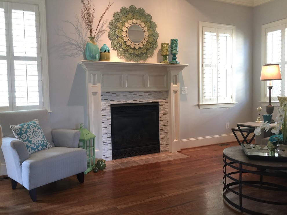 Design ideas for a mid-sized traditional open concept family room in Raleigh with grey walls, medium hardwood floors, a standard fireplace, a tile fireplace surround, no tv and brown floor.